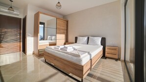 Een moderne slaapkamer met een groot bed, houten hoofdbord, een kledingkast en een spiegel.