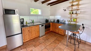 A kitchen with wooden cabinets, a stainless steel refrigerator, a dishwasher, and a bar stool.