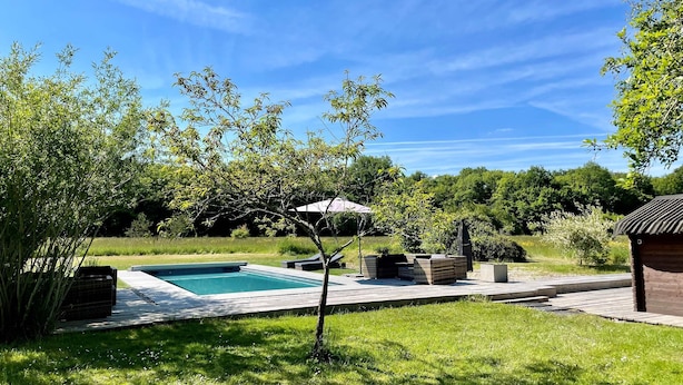 A backyard with a swimming pool, outdoor furniture, and a pergola.