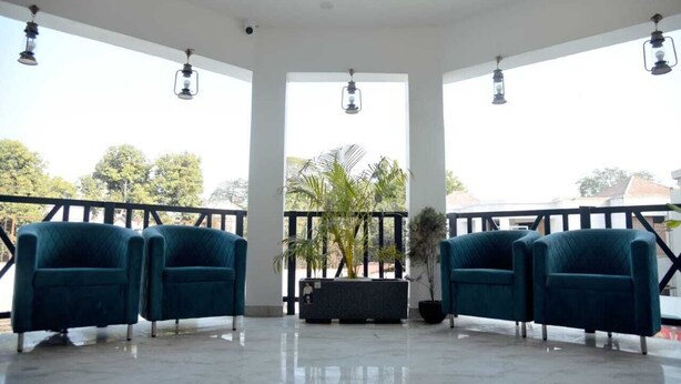 A spacious balcony with two teal armchairs, a black planter with plants, and a railing. - eco park (Huzur)