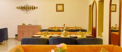A dining area with round tables set for four, blue upholstered booths, and a ceiling with recessed lighting.