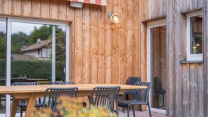 A wooden exterior with a large sliding glass door, a wooden deck, and outdoor seating. - Villa Madonne *Pool *Beach *7 sleeps ☀️ (Lège-Cap-Ferret)