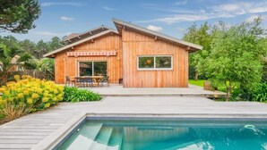 A wooden cabin with a pool, surrounded by lush greenery and a clear sky. - Villa Madonne *Pool *Beach *7 sleeps ☀️ (Lège-Cap-Ferret)
