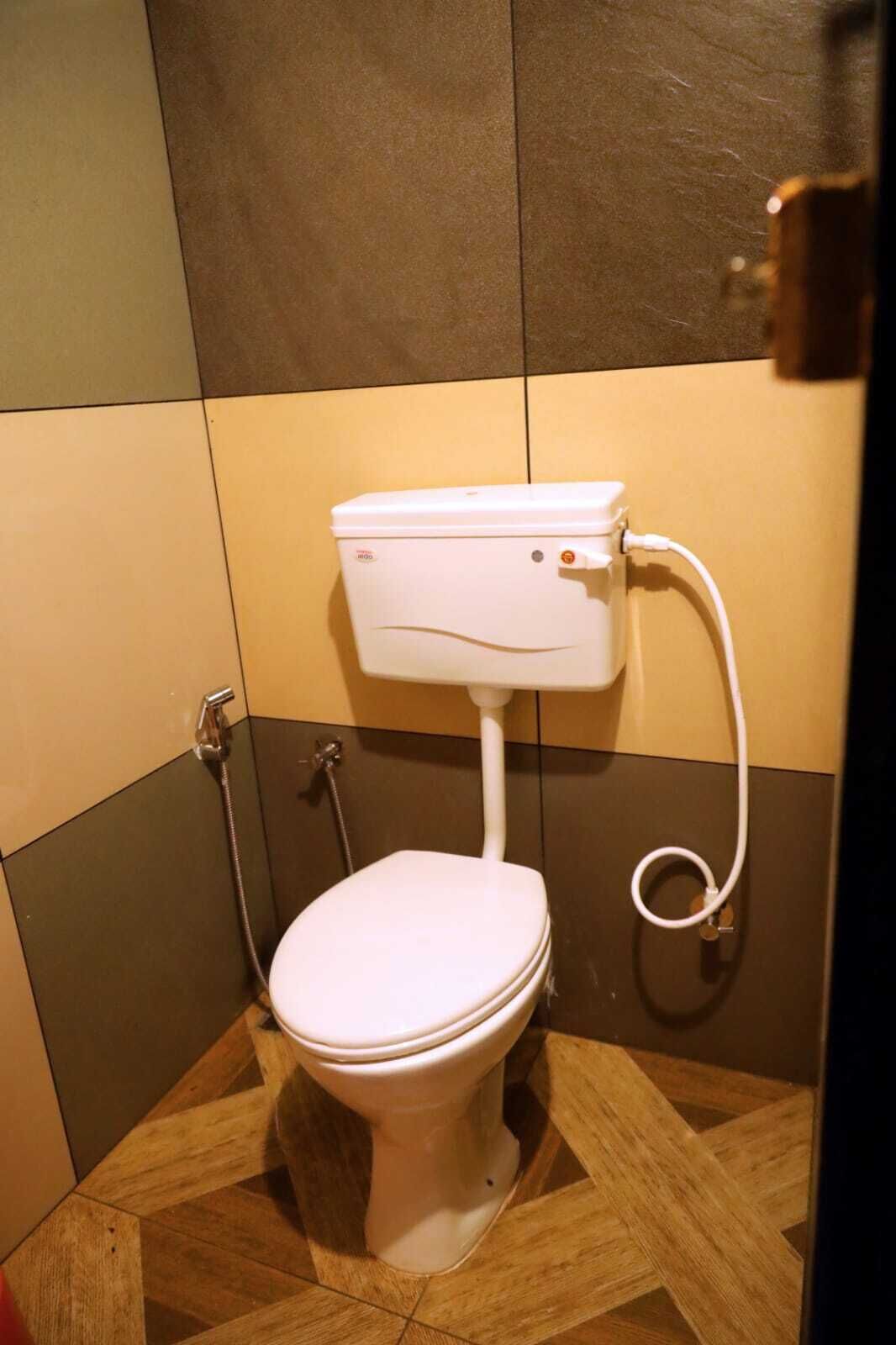 Een kleine badkamer met een wit toilet, een douche en een betegelde vloer.