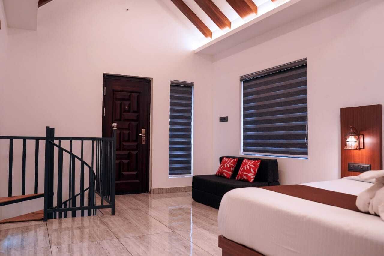 A hotel room with a bed, a sofa, a staircase, and a door.