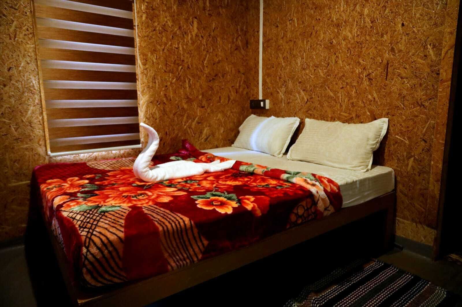 A bed with a floral bedspread and a swan-shaped pillow.