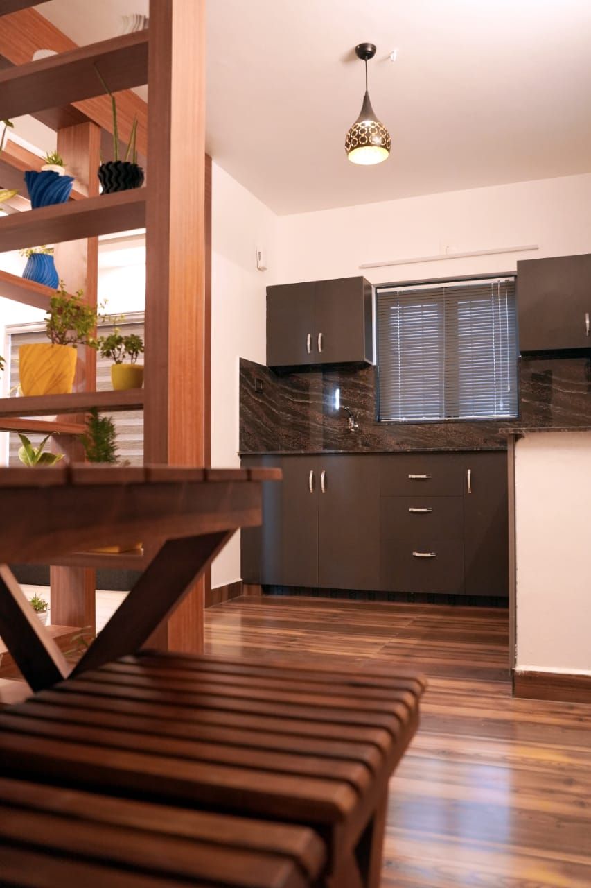Una cocina moderna con armarios oscuros, encimera de mármol y una lámpara colgante.