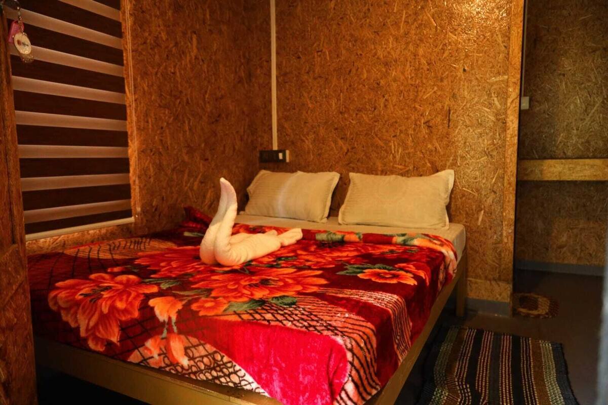 A bed with a floral bedspread, a swan-shaped pillow, and a striped rug.