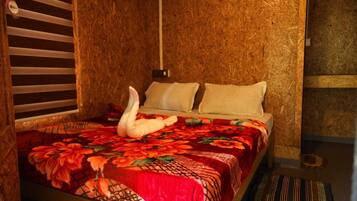 A bed with a floral bedspread, a swan-shaped pillow, and a striped rug.