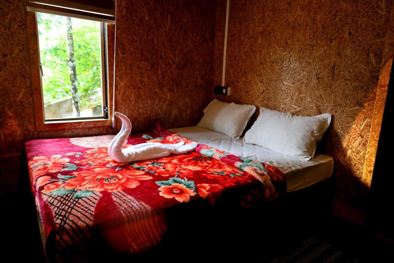 A room with a bed, a window, and a swan-shaped towel on the bed.