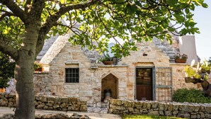 Une maison en pierre avec une porte en bois, une fenêtre et un petit arc.