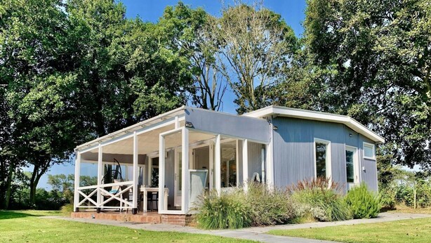 A single-story house with a covered porch and a large window. - Coastal Hideaway Bungalow With Garden (Sint Maartensvlotbrug)