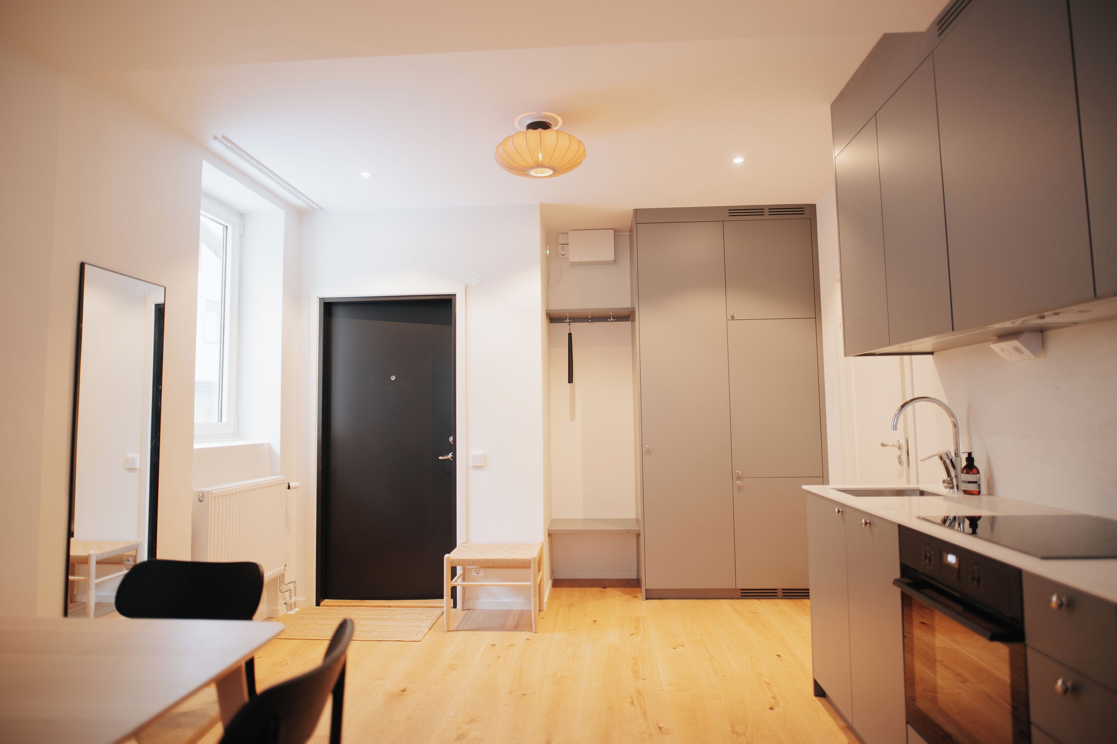 A modern kitchen with a wooden table, chairs, and a built-in oven.