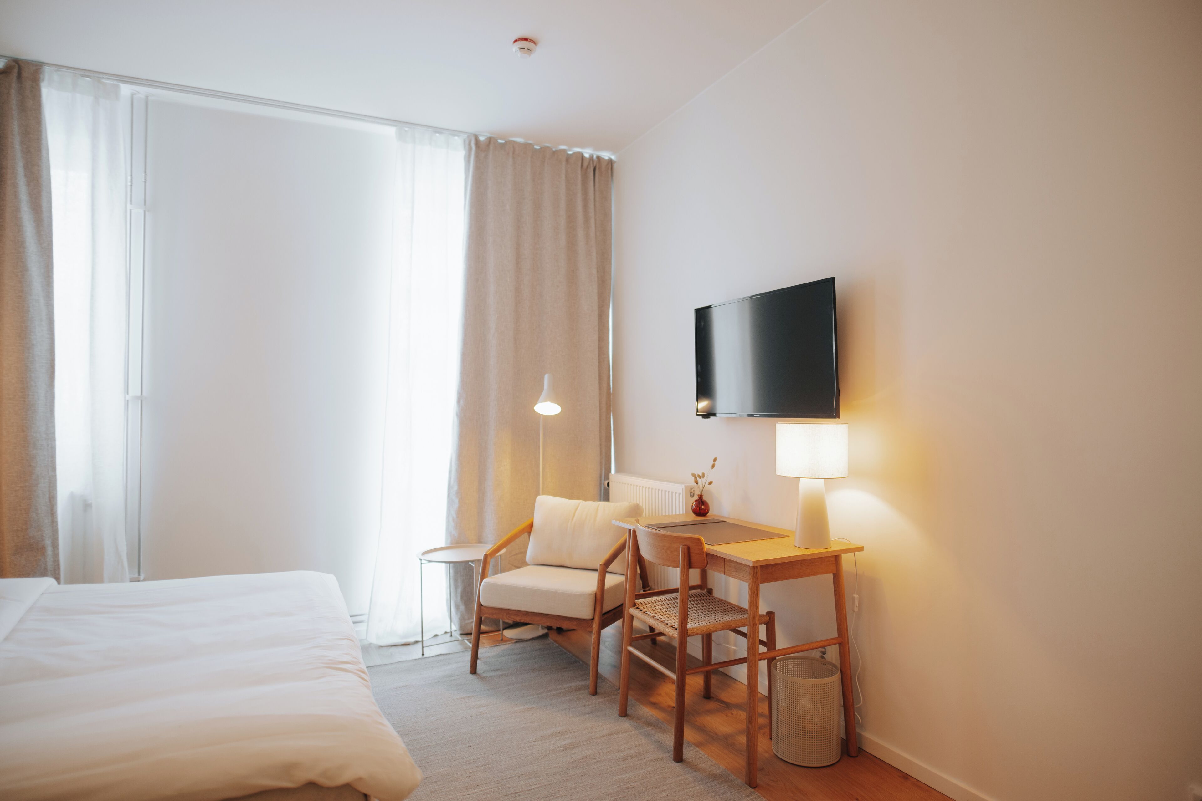 Una habitació d'hotel amb un llit, un escriptori amb una cadira, una televisió i una làmpada.