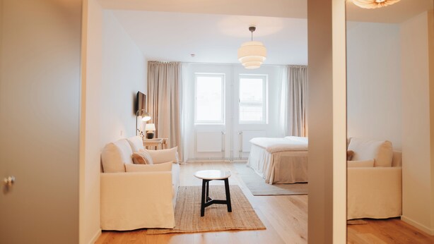 Quarto de hotel moderno com sofá, uma mesinha e uma cama.