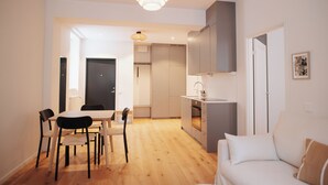 Uma sala de estar moderna com sofá, mesa de jantar com cadeiras e área de cozinha com armários e pia.