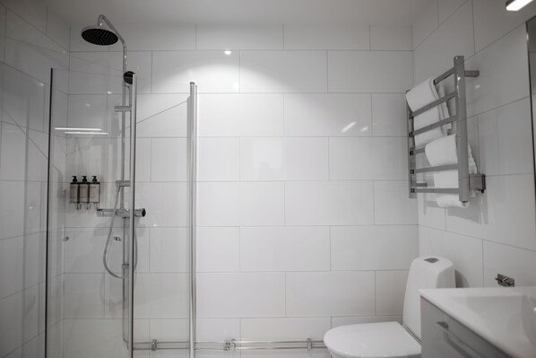 A modern bathroom with a glass-enclosed shower, a white toilet, and a towel rack.