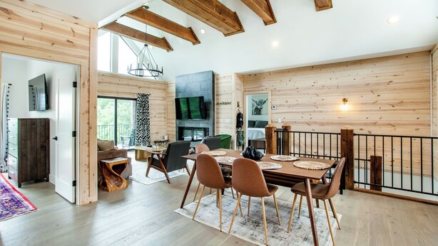 Un vaste espace dédié à la salle à manger, avec une table et des chaises en bois, une cheminée et une vue sur l’extérieur.