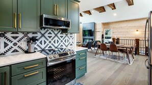 Une cuisine moderne avec des meubles de couleur verte, un four à micro-ondes et une cuisinière. On y trouve également un coin repas avec une table et des chaises.