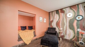 A room with a bed, a small table, and a chair. There is a window and a wall with a patterned design. - Extended Stay | Spacious Kitchen Studio | Free Parking (Prescott)