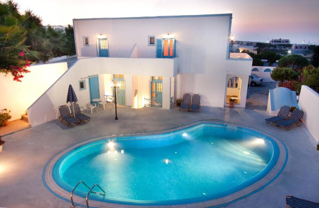 A modern building with a swimming pool, lounge chairs, and a view of the surrounding area.
