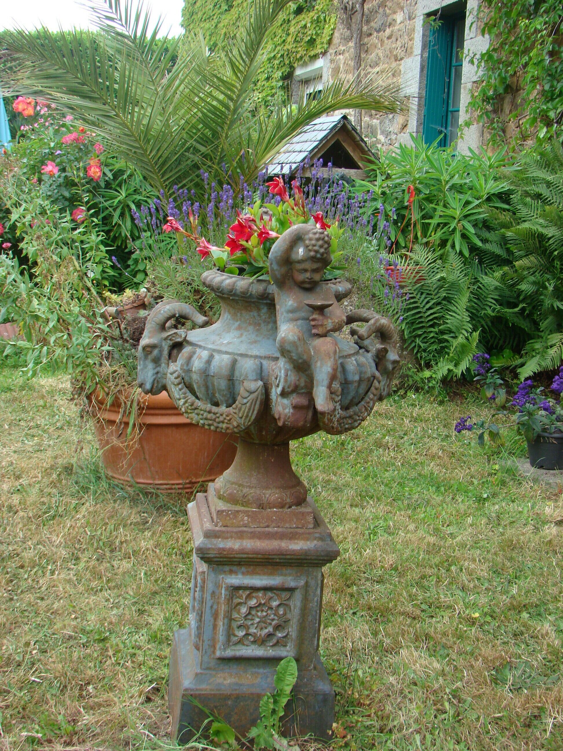 A garden with a decorative fountain featuring a sculpture of a child and a ram.