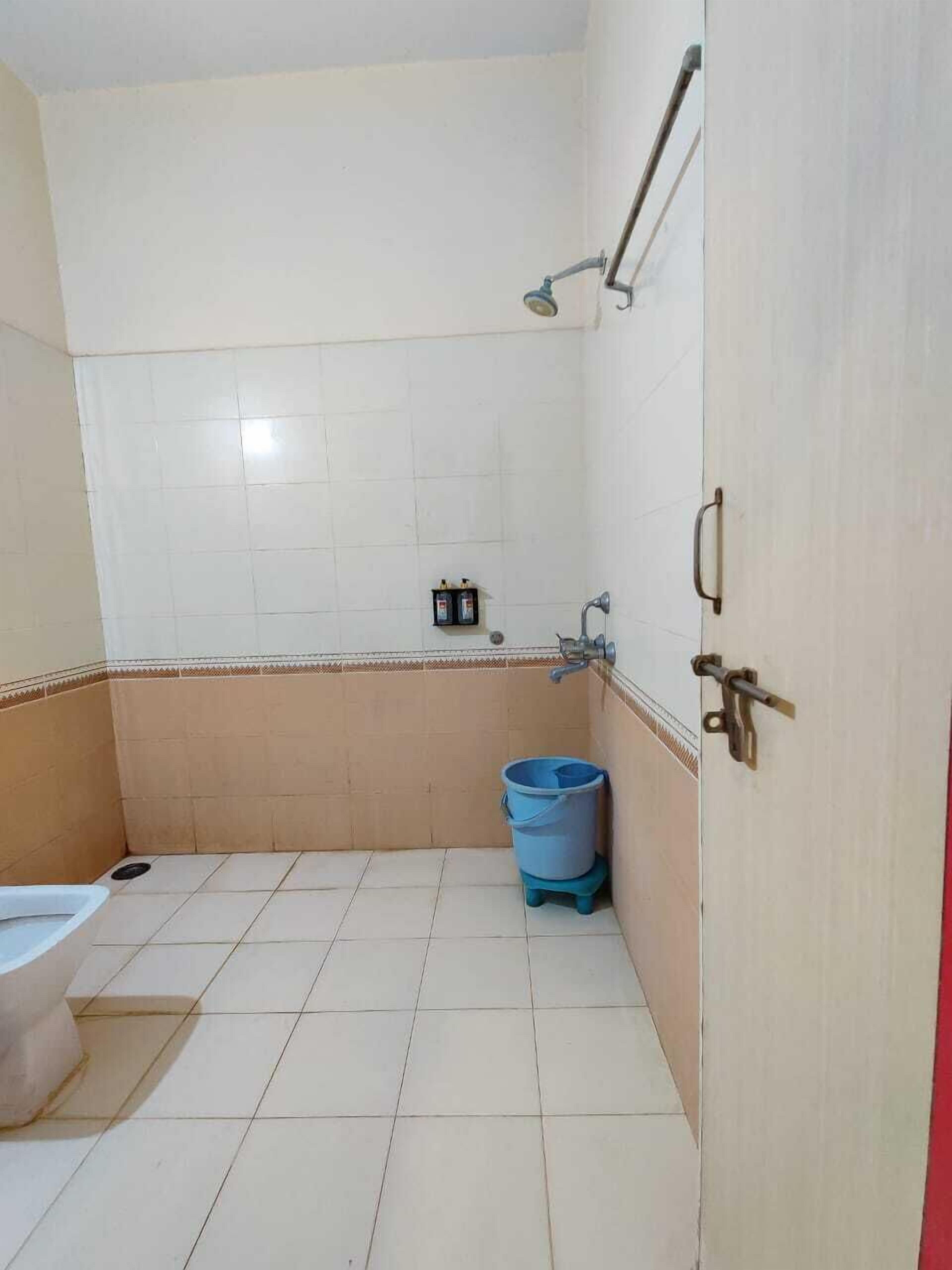 Un baño con inodoro, ducha y un cubo azul.