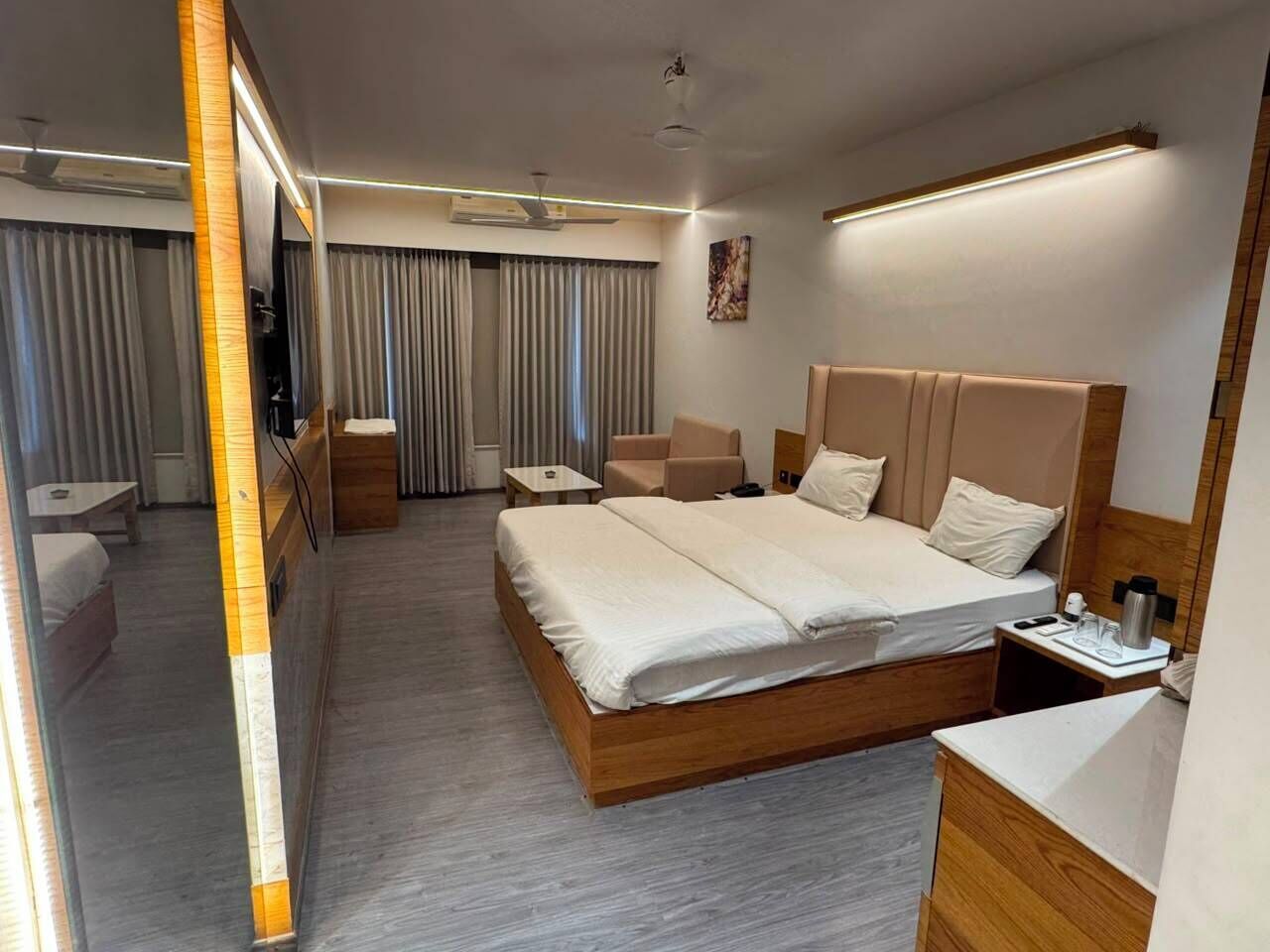 Una habitación de hotel moderna con una cama grande, mesitas de noche, un escritorio y una zona de estar.