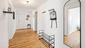 A hallway with wooden flooring, a mirror, a coat rack, and a small table with a plant. - Vacation apartment Hirschegg, 2 x bath 5Z 10 beds kitchen 2 parking spaces, WLAN (Bad Friedrichshall)