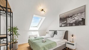 A modern bedroom with a skylight, a bed with green bedding, a bedside table with a lamp, and a large cityscape painting on the wall. - Vacation apartment Hirschegg, 2 x bath 5Z 10 beds kitchen 2 parking spaces, WLAN (Bad Friedrichshall)