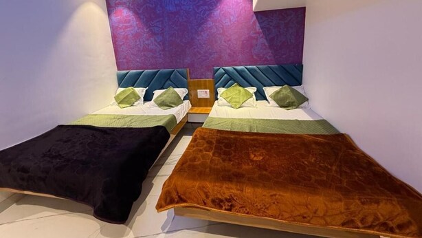 A modern hotel room with two beds, a ceiling light, and a decorative wall. - Hotel Madhuban (Khuldabad)