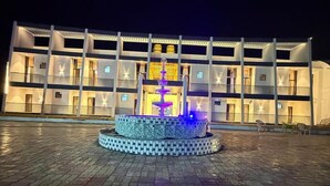 A multi-story building with a central fountain, paved courtyard, and outdoor seating area. - Hotel Madhuban (Khuldabad)