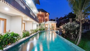 A modern hotel with a swimming pool, a covered outdoor area, and lush greenery. - Juli House (Ubud)