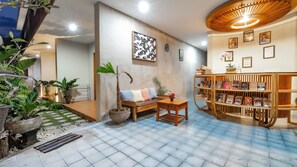 A cozy living area with a wooden bench, a bookshelf, and potted plants. - Juli House (Ubud)