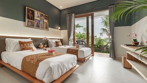 A hotel room with two beds, a large window with curtains, a painting on the wall, and a small table with a plant. - Juli House (Ubud)