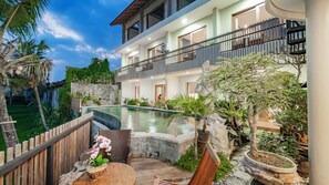 A modern hotel with a swimming pool, outdoor seating, and lush greenery. - Juli House (Ubud)