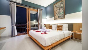 A hotel room with a bed, a nightstand, a painting, and a balcony with curtains. - Juli House (Ubud)