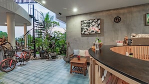 A spacious indoor area with a curved bar, seating, and a spiral staircase. - Juli House (Ubud)