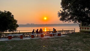Une vue sur le coucher de soleil, avec des bancs le long d’un sentier qui longe la rivière.
