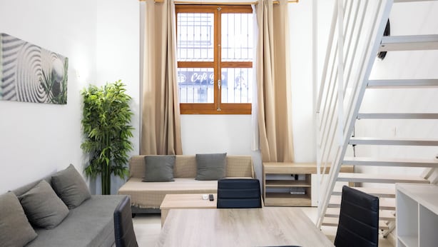 Una sala de estar moderna con un sofá, una mesa de comedor y una escalera.