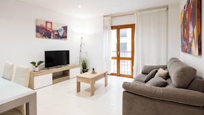 Una sala de estar moderna con un sofá, un televisor sobre un mueble de madera, una mesita y un cuadro en la pared.