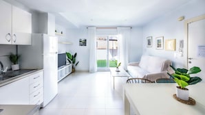Una cocina moderna con armarios blancos, un refrigerador y una zona de comedor con mesa y sillas.