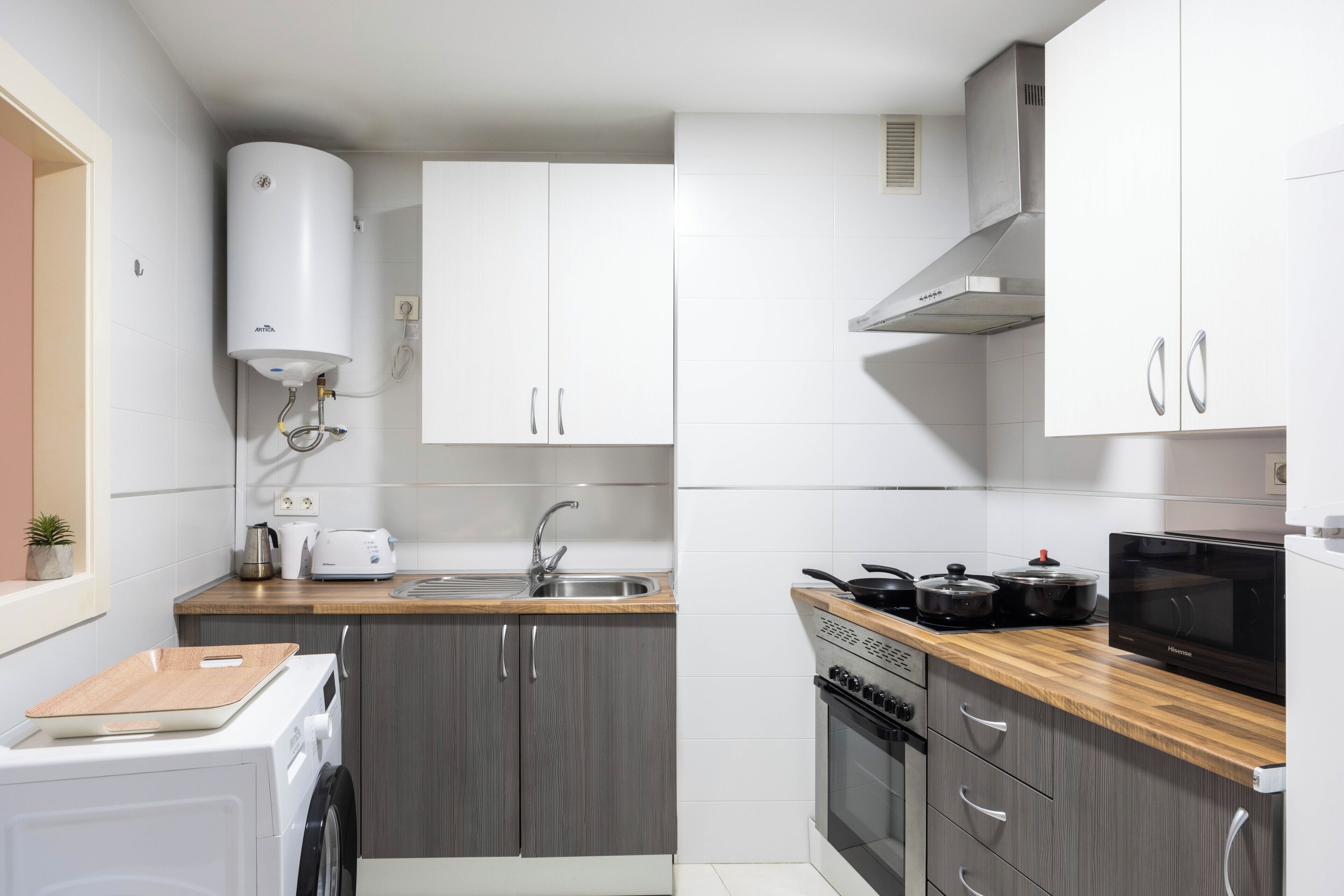 Una cocina moderna con gabinetes grises, horno empotrado, microondas y un lavamanos.