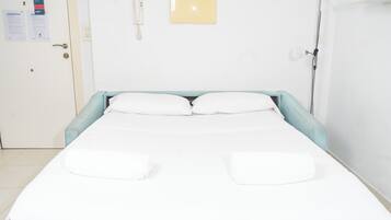 A hotel room with a bed, a bedside phone, and a wall-mounted light fixture.