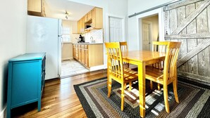 A compact kitchen with wooden cabinets, a dining table with chairs, and a ceiling fan. - Trojan Hideaway on First Street (Upland)