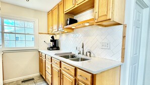 A kitchen with wooden cabinets, a double sink, and a window. - Trojan Hideaway on First Street (Upland)