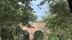 A street view with a brick archway, cars, and greenery. - Elegant Apartment in the center of Rome (Roma)