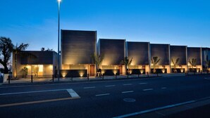 A modern building with a series of large, rectangular windows and a well-lit entrance.