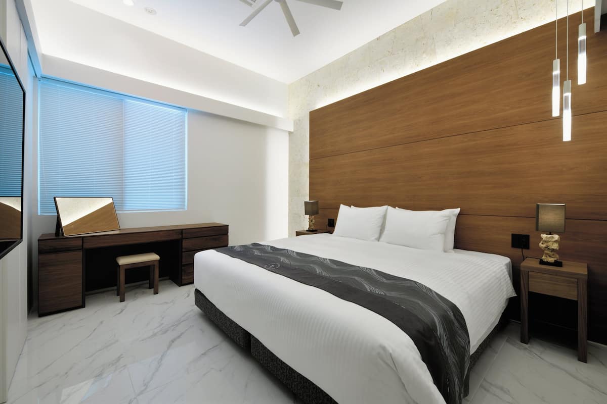 A modern bedroom with a large bed, a desk, and a chair.