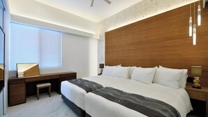 A modern hotel room with a large bed, a desk, and a chair.